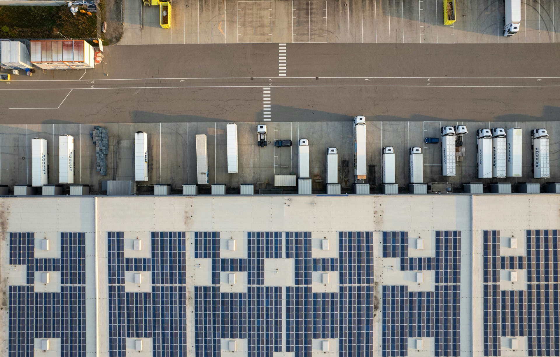 Solar-panelled warehouse roof with truck fleet from above